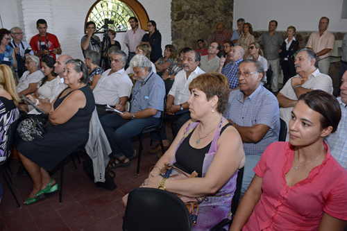 Personas sentadas, fotógrafos y camarógrafos durante la presentación de la unidad de descentralización